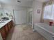 Bright bathroom featuring double sinks, tiled floors, walk-in shower, and relaxing tub at 5507 Gemini Bridges St, Las Vegas, NV 89130