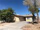 A cozy single-story home featuring a neutral exterior, xeriscaped landscaping, and mature trees at 6196 W University Ave, Las Vegas, NV 89103