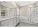 Bright bathroom featuring a double sink vanity, soaking tub, and glass-enclosed shower at 7051 Denio Island St, North Las Vegas, NV 89084