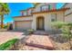 Charming two-story home with red brick driveway and walkway with manicured landscaping and tan stucco at 708 Point Bluff St, Henderson, NV 89002