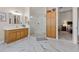 Bright bathroom featuring marble floors, wooden cabinets, a glass shower, and an open doorway to the bedroom at 7411 Brittlethorne Ave, Las Vegas, NV 89131