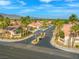 View of the beautiful gated community entrance with lush landscaping, mature palm trees, and desert mountain views at 7411 Brittlethorne Ave, Las Vegas, NV 89131
