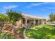 Charming home with a well-manicured lawn, covered patio, and beautiful landscaping with mature trees and stone accents at 7411 Brittlethorne Ave, Las Vegas, NV 89131