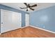 Bright bedroom features wood floors, a ceiling fan, closet, and fresh blue paint at 7824 Faith Ct, Las Vegas, NV 89131