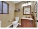 Half bathroom features a single vanity, wood-look floors, decorative mirror, and window with privacy blinds at 8224 Fawn Meadow Ave, Las Vegas, NV 89149