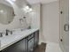 Modern bathroom with dual sinks, granite countertops, dark wood cabinets, glass shower, and elegant lighting at 8224 Fawn Meadow Ave, Las Vegas, NV 89149
