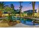 Beautiful backyard pool with lush landscaping, rock features, and ambient lighting, perfect for relaxation at 8224 Fawn Meadow Ave, Las Vegas, NV 89149