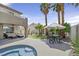 Backyard featuring a patio, dining set, and spa surrounded by lush landscaping and shade trees at 928 Aspen Valley Ave, Las Vegas, NV 89123