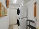 Efficient laundry area with stacked washer and dryer, storage shelves, and tiled floor at 928 Aspen Valley Ave, Las Vegas, NV 89123
