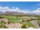 Expansive aerial view showcasing a golf course set against a backdrop of majestic mountains at 11 Misty Peaks Ct, Las Vegas, NV 89135