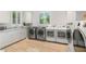 A large laundry room with white cabinets, stone countertops and multiple washing machines at 11 Misty Peaks Ct, Las Vegas, NV 89135