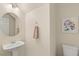 Bright half bath with pedestal sink, round mirror, artwork and tile floors, adjacent to the toilet at 11226 Kenyan Sunshine Ct, Las Vegas, NV 89138