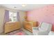 Cozy Bedroom featuring a crib, a changing table and a comfy chair with pink walls and star decals at 11226 Kenyan Sunshine Ct, Las Vegas, NV 89138