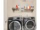 Functional laundry room with modern washer and dryer units and shelving at 2806 Calle Cadiz, Henderson, NV 89044