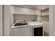 Modern laundry room featuring a front loading washer and dryer with shelf and clothes hanging bar above at 4044 Villeroy Ave, Las Vegas, NV 89141