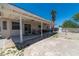 Spacious backyard with a covered patio, mature palm tree, rock landscaping, and room for outdoor activities at 475 E Robindale Rd, Las Vegas, NV 89123