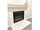Close up of the white tiled fireplace with black trim, light wood mantle and white marble hearth at 5191 Caliente St # 84, Las Vegas, NV 89119