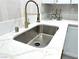 Close-up of a kitchen sink with quartz countertops and white cabinets with gold hardware at 5191 Caliente St # 84, Las Vegas, NV 89119