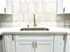 Close-up of a kitchen sink with quartz countertops and white cabinets with gold hardware at 5191 Caliente St # 84, Las Vegas, NV 89119