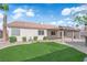 Beautiful backyard featuring a grassy lawn, covered patio, mature landscaping, and a light-colored exterior at 5437 Escallonia St, Las Vegas, NV 89149