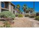 Exterior shot of a condo with desert landscaping, gravel, flowers, and some palm trees at 595 Sellers Pl, Henderson, NV 89011