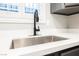 Close up on a stainless steel kitchen sink under a window, set in a white countertop at 595 Sellers Pl, Henderson, NV 89011