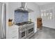 Gourmet kitchen featuring a large stainless steel stove, range hood, blue backsplash and white cabinets at 6173 Sabine Ranch Rd, Las Vegas, NV 89131