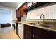 Kitchen featuring granite counters, tile backsplash, dark cabinets, modern appliances, and washer/dryer at 634 Oakmont Ave # 1903, Las Vegas, NV 89109