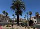 The community entrance surrounded by mature palms, desert landscaping, and a roundabout at 855 N Stephanie St # 2311, Henderson, NV 89014
