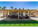 Spacious backyard with covered patio, seating area, lush artificial grass, and mature palm trees at 906 Sitting Bull Dr, Henderson, NV 89014
