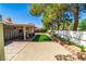 A wide backyard with trees, artificial grass, and a covered patio with chairs at 906 Sitting Bull Dr, Henderson, NV 89014