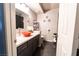 A modern bathroom featuring a unique orange sink bowl and dark gray cabinets at 906 Sitting Bull Dr, Henderson, NV 89014