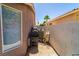 A view of the small side yard with a grill, wheelbarrow, and window at 906 Sitting Bull Dr, Henderson, NV 89014