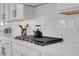 Close-up of a white kitchen countertop with a gas cooktop and subway tile backsplash at 9643 Wildflower Vista Ave, Las Vegas, NV 89166