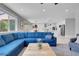 Bright living room with a large blue sofa, light wood floors, and an open concept kitchen at 9643 Wildflower Vista Ave, Las Vegas, NV 89166