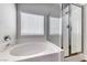 Close up of bathtub and glass shower stall in modern bathroom with a bright window at 9766 Marcelline Ave, Las Vegas, NV 89148