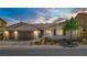 Charming single-story home featuring manicured landscaping, a three-car garage and tasteful curb appeal at sunset at 9779 Mosaic Canyon Ct, Las Vegas, NV 89149