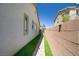Narrow side yard featuring well-maintained artificial grass, a brick pathway, and tall privacy walls at 9779 Mosaic Canyon Ct, Las Vegas, NV 89149