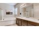 Well-lit bathroom boasts a soaking tub, dual vanities, and a separate glass shower at 10262 Havasu Falls St, Las Vegas, NV 89141