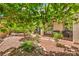 Tranquil backyard with a custom fire pit, mature trees, and a covered patio area for relaxation at 11625 Cabo Del Verde Ave, Las Vegas, NV 89138
