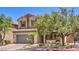 Charming two-story home with a gray garage door and desert landscaping and manicured green foliage at 11625 Cabo Del Verde Ave, Las Vegas, NV 89138