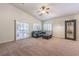 Spacious living room with carpet, plantation shutters, ceiling fan, dark sofa, and decorative shelving at 11625 Cabo Del Verde Ave, Las Vegas, NV 89138