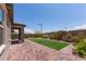 A backyard featuring a brick patio, a custom putting green, and colorful flowering bushes at 12565 Huckleberry Oak Ave, Las Vegas, NV 89138