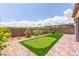 A manicured backyard featuring a custom putting green, brick patio, and mature flowering bushes at 12565 Huckleberry Oak Ave, Las Vegas, NV 89138