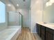 Bathroom featuring double sinks, a shower, a soaking tub, and wooden floors at 12565 Huckleberry Oak Ave, Las Vegas, NV 89138