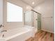 Bright bathroom featuring a shower over tub, wood look floors, and white cabinets at 12565 Huckleberry Oak Ave, Las Vegas, NV 89138