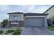 Two-car garage featuring a gray door, stone accents, and a paved driveway at 12565 Huckleberry Oak Ave, Las Vegas, NV 89138
