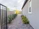 A view of the side yard featuring a brick paver walkway lined with colorful flowering plants and landscape lighting at 12565 Huckleberry Oak Ave, Las Vegas, NV 89138