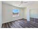 Bright bedroom featuring wood-look floors, a ceiling fan, a window with a view, and a closet with mirror doors at 1351 Huckleberry St, Pahrump, NV 89048