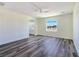 Spacious main bedroom featuring wood-look floors, a ceiling fan, a window with a view, and access to the bathroom at 1351 Huckleberry St, Pahrump, NV 89048